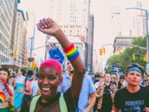 Connect with Aligned Organizations. A woman smiles raising her arm in a crowd of people marching together.